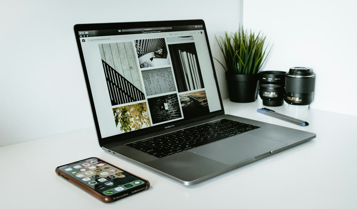 Laptop na białym biurku z otwartą stroną internetową galerii zdjęć.